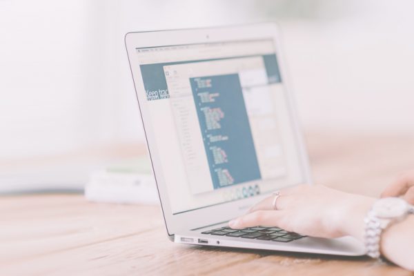 woman's hands typing on laptop at desk