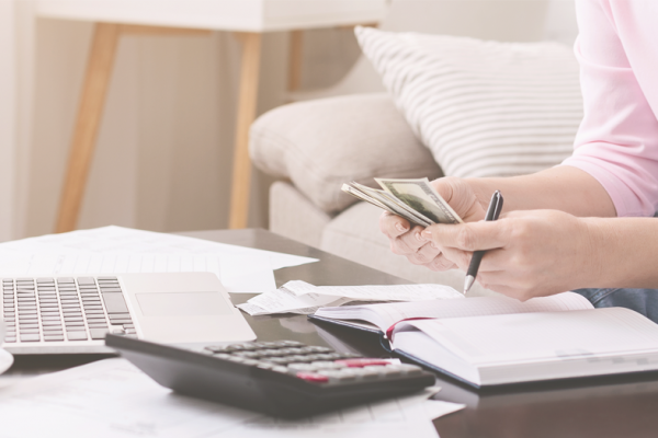 woman counting money sat by laptop