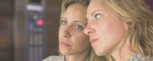 sad woman looking at her reflection as leaning against glass window