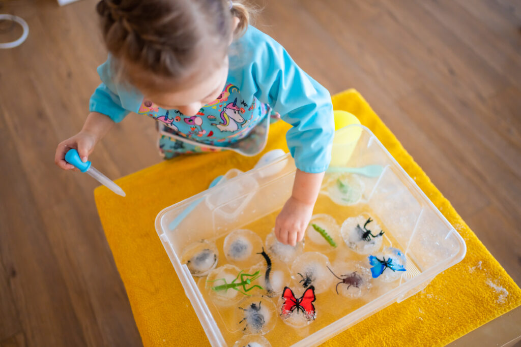 child playing with ice after her mum looked for taste-safe sensory play ideas for toddlers