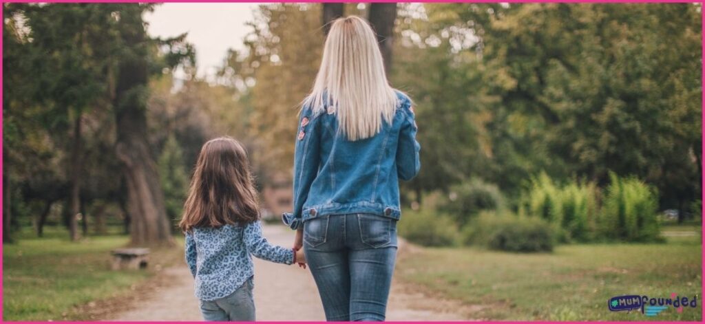 Mum and daughter walking in a park - Getting outdoors each day is one of my self-care tips for busy mums.