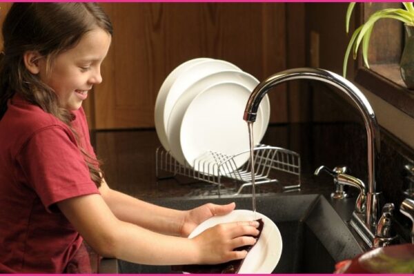 young girl washing dishes - age appropriate chores for children