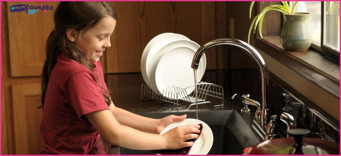 young girl washing dishes - age appropriate chores for children